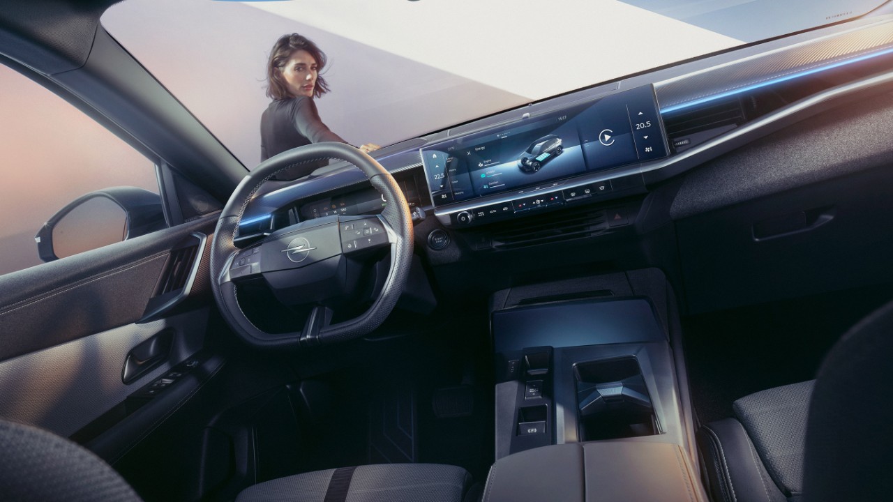 Close-up van het pure panel display systeem in een nieuwe Opel Grandland met een vrouw die op de auto leunt en naar binnen kijkt