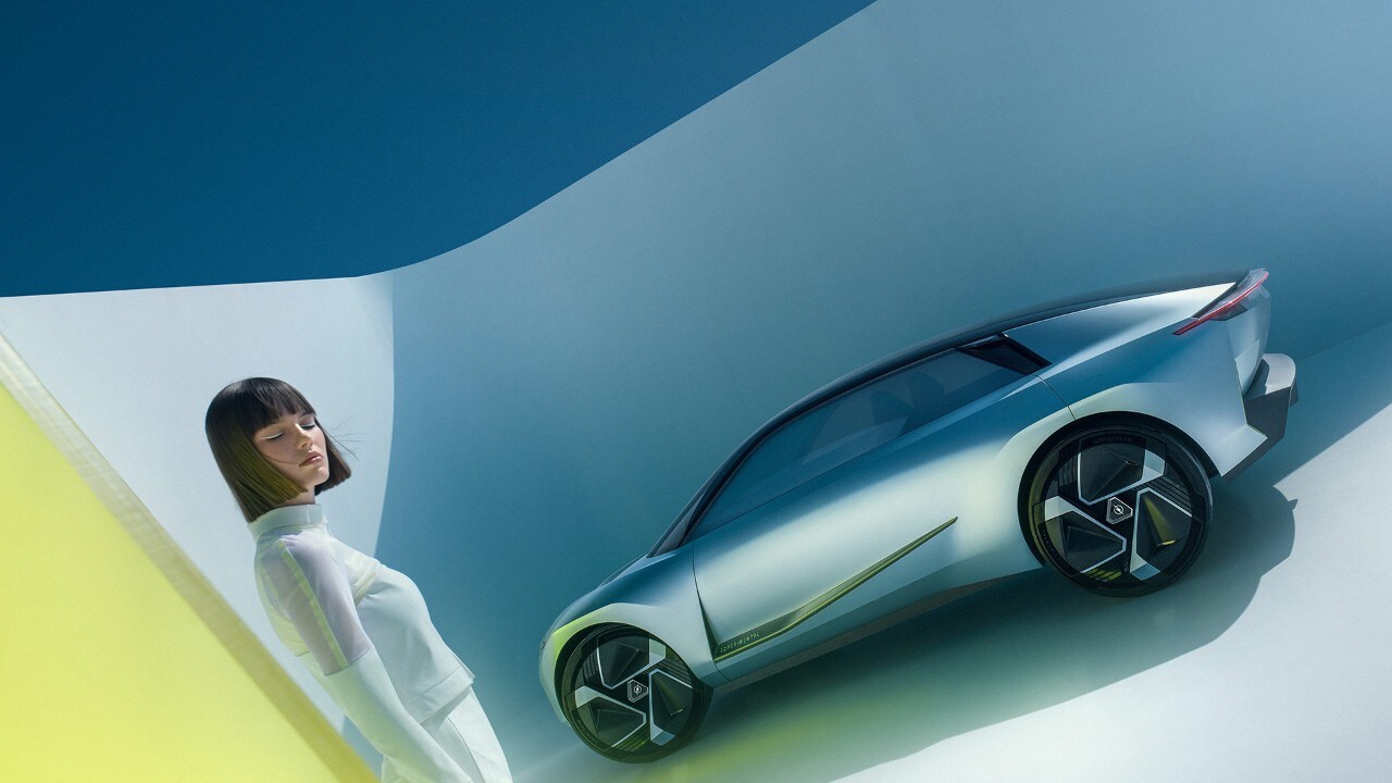 Zijaanzicht van een zilveren Opel Experimental waar een vrouw naast staat